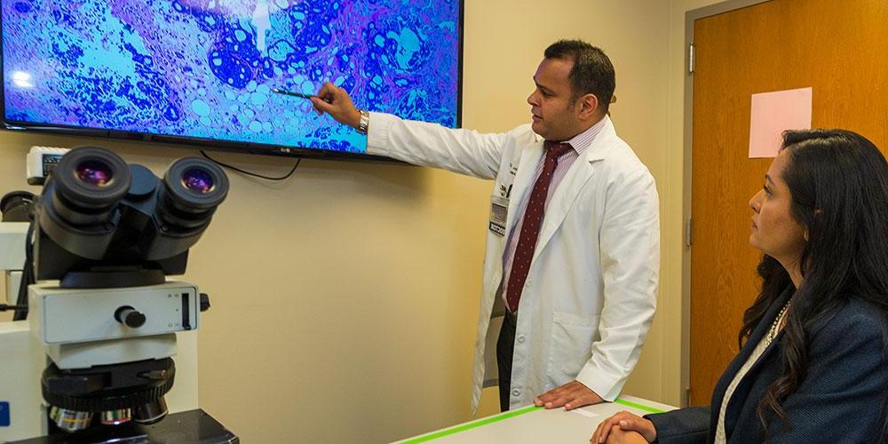 Dr. Mehta in the Biopsy Lab with microscope and TV.